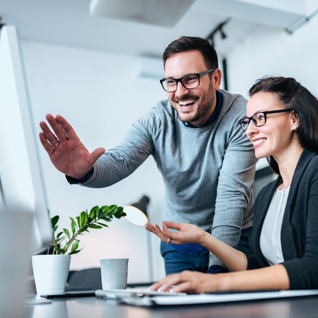 Mann und Frau schauen auf einen PC Bildschirm und sprechen über die Darstellung auf dem Monitor